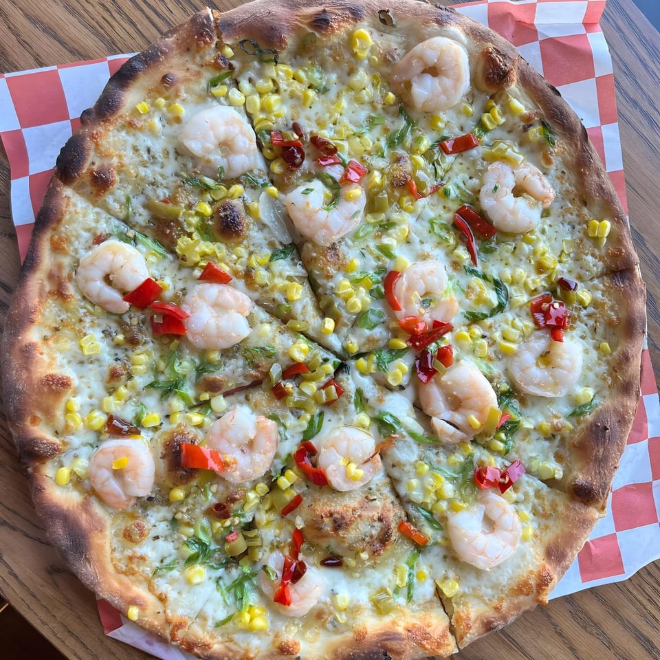 The Parlor's shrimp pizza with corn, red peppers, and green onions on a checkered paper.