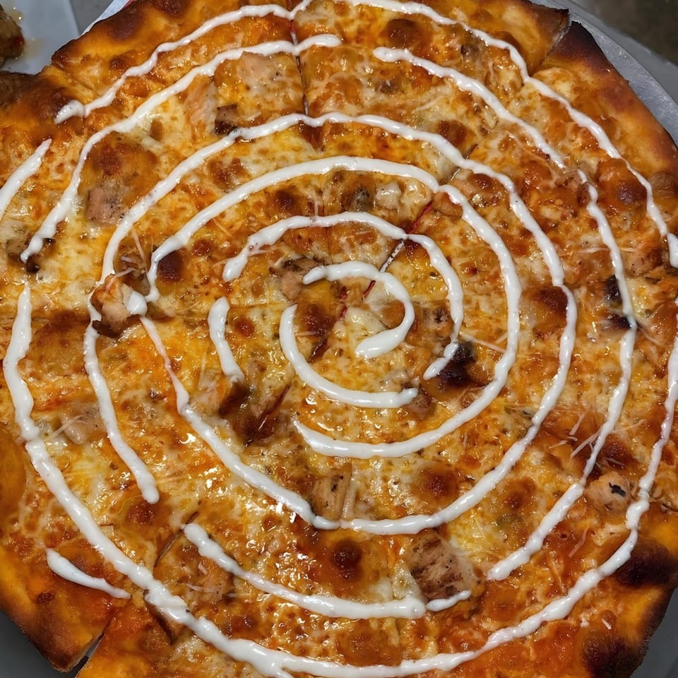 The Parlor's buffalo chicken pizza, topped with a spiral of white sauce, sliced and ready to eat.